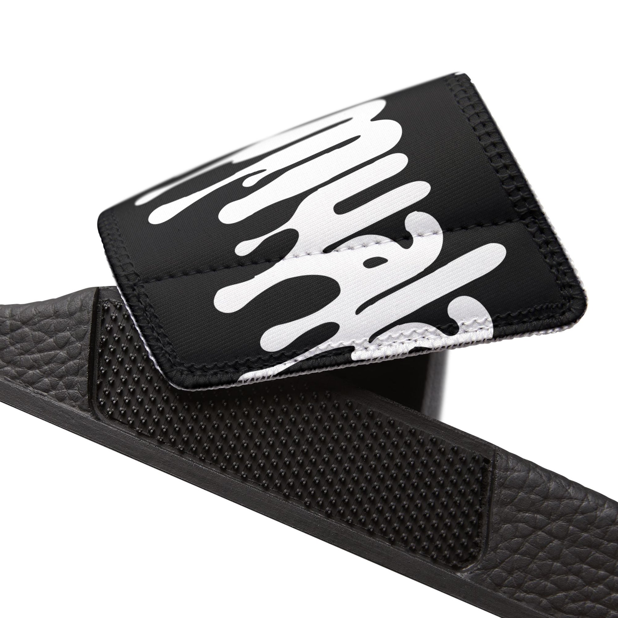 Close-up of black Muala® "flip fat flop" men's sandal strap with white graphic and textured footbed
